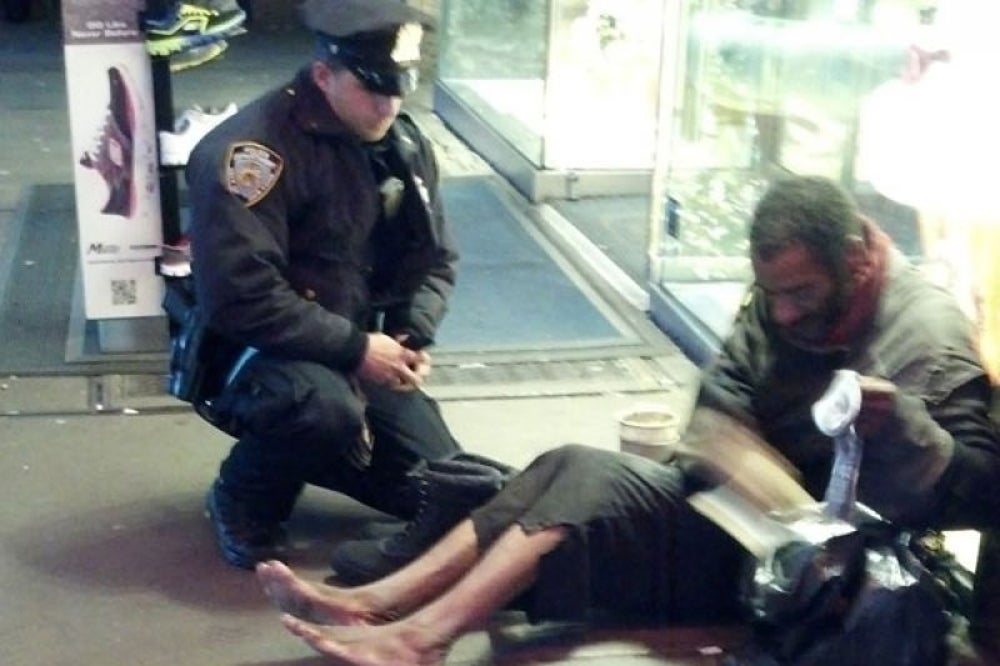 A police officer gives his shoes to a freezing homeless man.